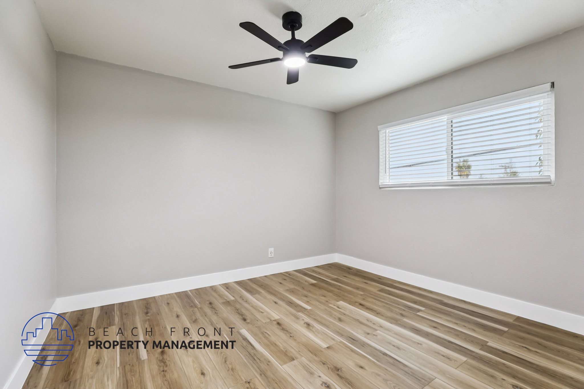A room with a ceiling fan and wooden flooring.